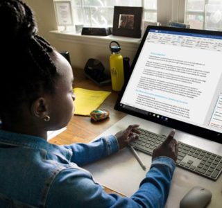 Young person using a wireless keyboard to work on a document in Microsoft Word on a large desktop monitor