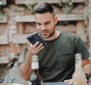 man in gray crew neck long sleeve shirt holding black smartphone