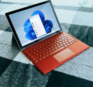 Red Surface laptop on a checkered bed by a window