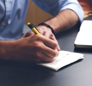 Free Person Writing on Paper Using Yellow and Black Pen Stock Photo