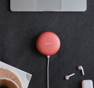 flat lay photography of coral Google Home Mini on black surface beside Apple AirPods