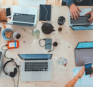 people sitting down near table with assorted laptop computers