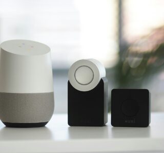 white and gray Google smart speaker and wo black speakers