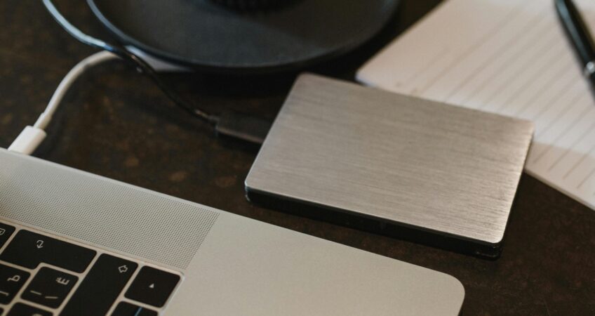 Free Closeup of an external hard drive connected to a laptop with a USB cable on a desk. Stock Photo