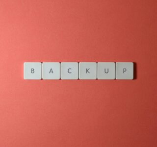 Free Close-up of keyboard keys spelling 'BACKUP' placed on a coral-colored surface. Stock Photo