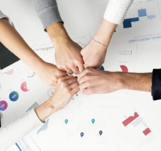 Free Colleagues celebrate success with a fist bump over financial charts depicting teamwork and unity. Stock Photo