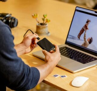 A man sitting at a table with a laptop and cell phone